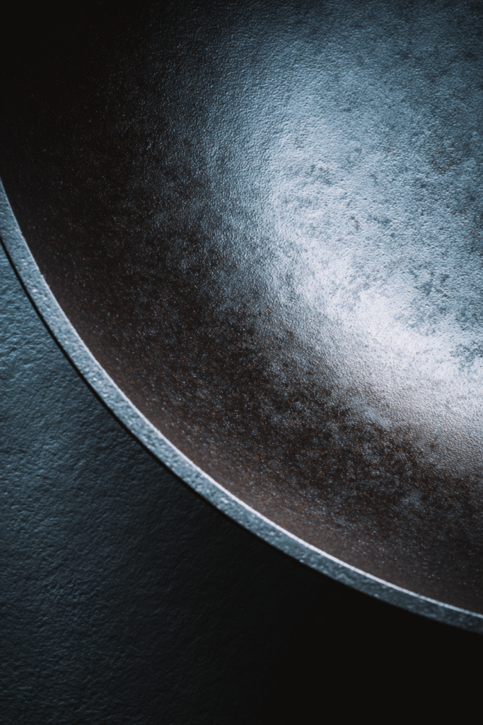 Macro close-up of a nonstick carbon steel wok surface showing smooth texture and light sheen, with slight egg residue — ideal for discussing coating quality and durability.